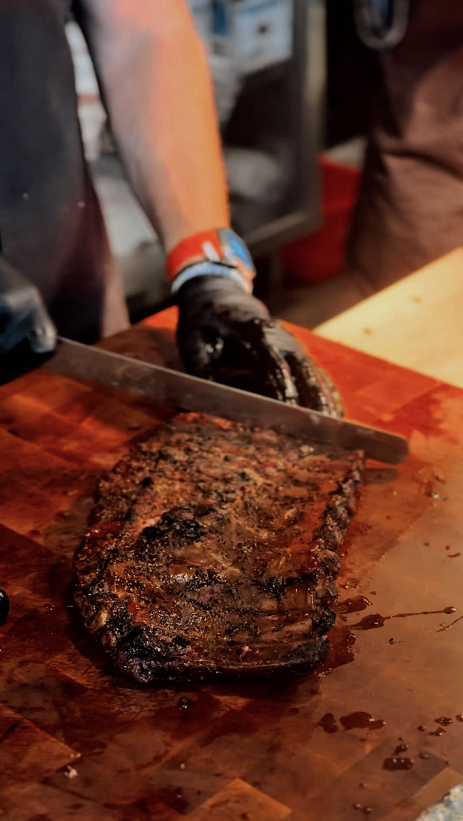 Brisket being sliced on a cutting board at Kenny J’s BBQ