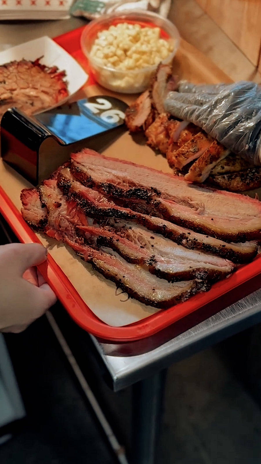 Sliced brisket and sides on a red tray at Kenny J’s BBQ in South Jordan